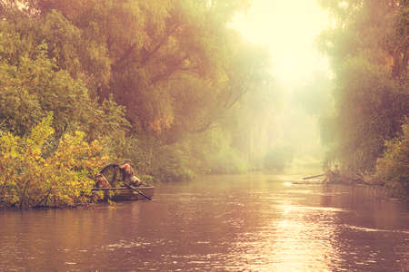 Professional fisherman in small boats on misty river in the Danube Delta in Romaniaの写真素材