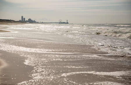 A beach on an overcast day with a city skyline in the distanceの写真素材