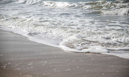 Close-up of waves and white foam of seawater on the beachの写真素材