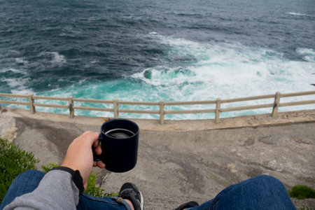 Drinking coffee sitting near the seaの写真素材