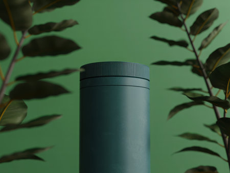 A dark teal cylindrical object sits centered, framed by out-of-focus lush green leaves casting soft shadows. The composition evokes a sense of calm and natural elegance.の素材
