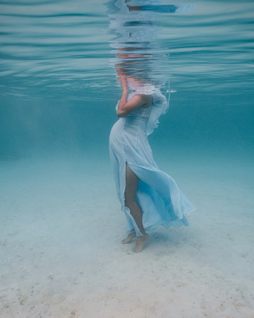 Young pregnant woman showing baby bump for an underwater photo shoot.の写真素材
