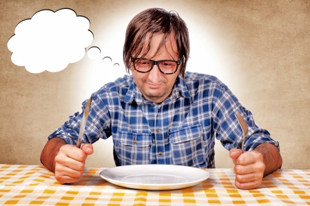 Sad man siting with empty plateの写真素材