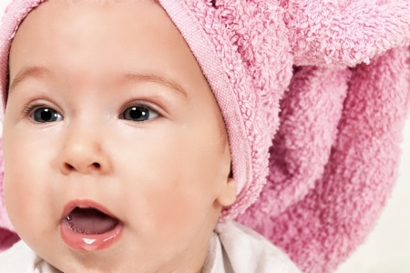 Beautiful baby girl with pink towelの写真素材