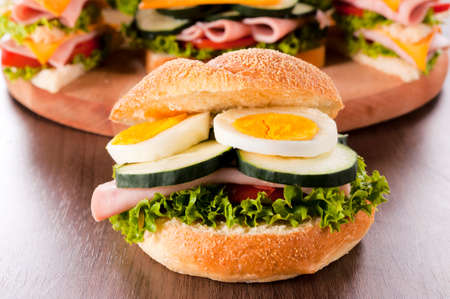 Big tasty sandwich with eggs and ham on wooden tableの写真素材