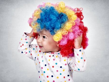 Happy little baby with clown wig on her head の写真素材