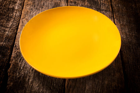 Empty yellow plate on the wooden backgroundの写真素材