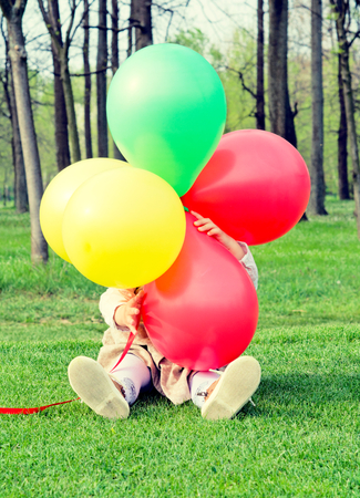 Little child hiding behind the colorful balloons の写真素材