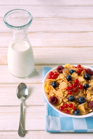 Cereal with berry fruit in the bowl from above on wooden table