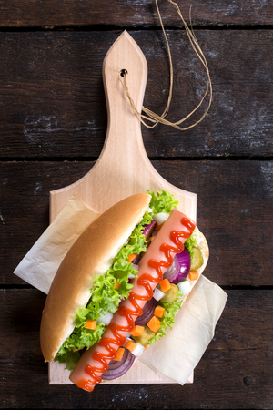 Hot dog with ketchup and vegetables feom above on wooden backgroundの写真素材