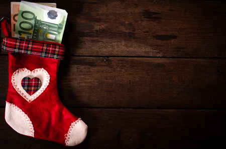 Traditional Christmas sock with the money on wooden wall with blank spaceの写真素材