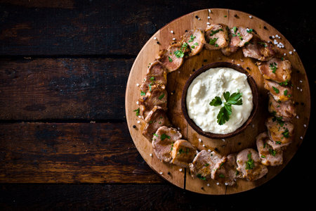 Slices of grilled meat and cheese cream on wooden background with blank spaceの写真素材