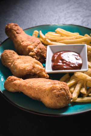 Fried chicken legs and French fries with bbq sauce in the plate,selective focusの写真素材