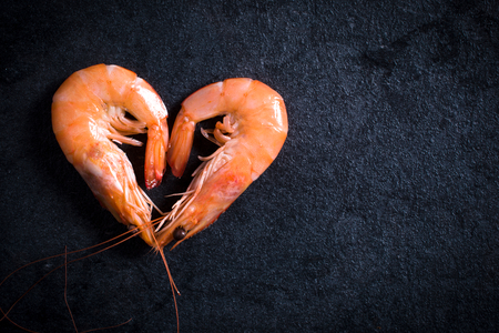 Boiled tiger shrimps heart shape on table with blank space on the right sideの写真素材