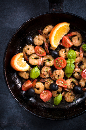 Fried tiger shrimps with ingredients in the pan from above on dark backgroundの写真素材