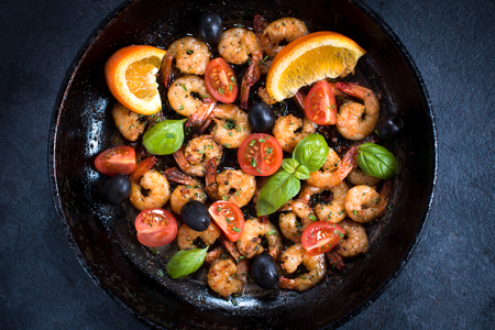 Fried tiger shrimps with ingredients in the pan from above on dark backgroundの写真素材