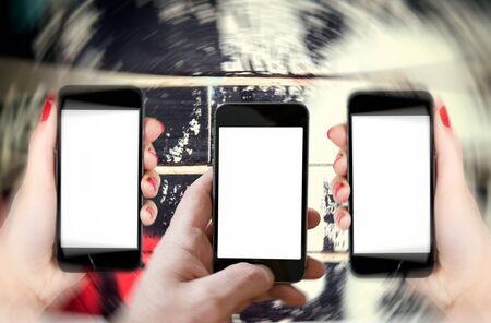 Man holding phone with blank screen and blurred motion of side phonesの写真素材