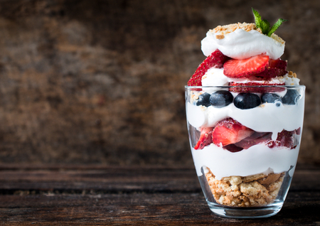 Sweet dessert in glass with biscuit,berry fruit and whipped cream,selective focus and blank space