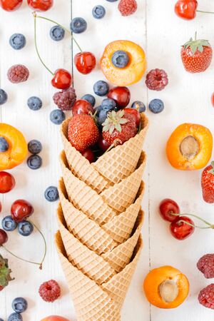 Fruits in the ice cream cone with from above on white wooden backgroundの写真素材