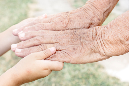 Young hand holding old senior hand,selective focusの写真素材