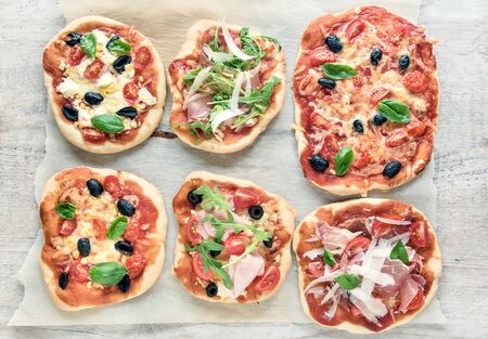 variety of mini pizzas from above on wooden tableの写真素材