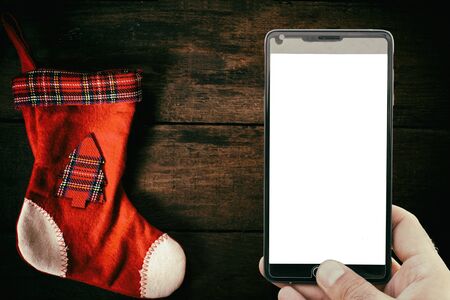 Traditional Christmas sock and blank screen on mobile phone on wooden backgroundの写真素材