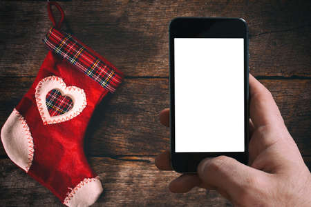 Traditional Christmas sock and blank screen on mobile phone on wooden backgroundの写真素材