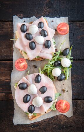 Sandwiches with mozzarella cheese,ham and vegetables on wooden backgroundのeditorial素材