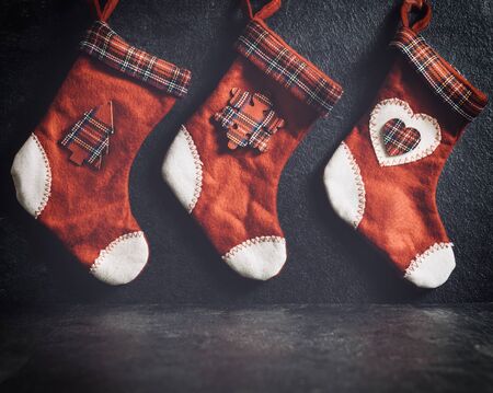 Traditional red Christmas socks hanging on the dark backgroundの写真素材