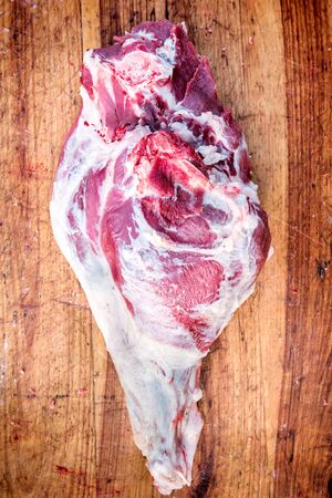 Raw whole raw and bloody pork leg on wooden backgroundの写真素材