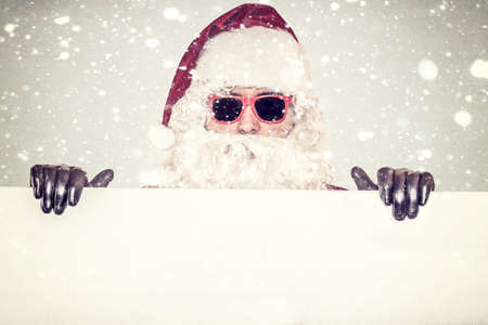 Santa Claus holding white billboard with snow in backgroundの写真素材