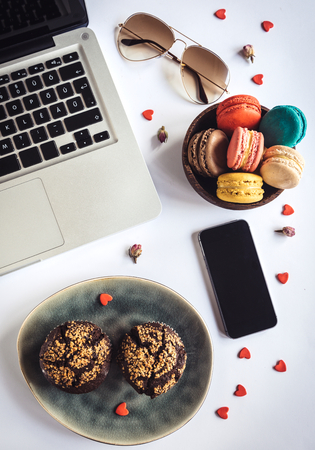 Sweet office concept with muffins and colorful macaroons cookies,selective focusの写真素材