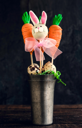 Carrots and bunny cake pops in the metal glass on wooden backgroundの写真素材