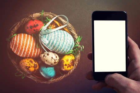 Colorful Easter eggs from above on dark background with blank space on smart phone screenの写真素材
