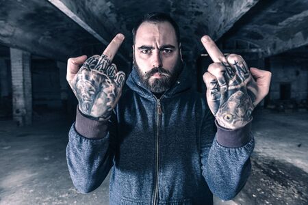 Man with tattooes on his hands showing middle fingers,selective focus