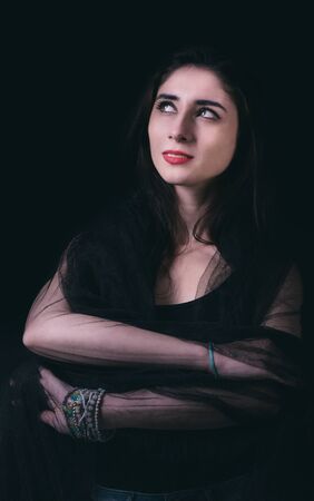 Beautiful young woman portrait on dark background in low key techniqueの写真素材