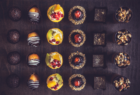 Assorted of fruit and chocolate mini cakes on the tableの写真素材