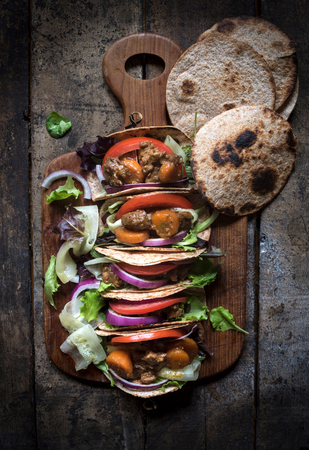 Mini tortilla sandwiches with vegetables salad and ground meat on the wooden background の写真素材