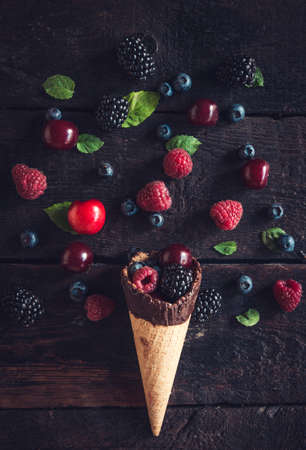 Fresh berries fruits and ice cream cone on the wooden backgroundの写真素材