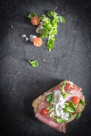 Sandwich with cream cheese and prosciutto on dark background with blank spaceの写真素材