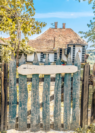 Old vintage house in the background and blank wooden board in front fenceの写真素材