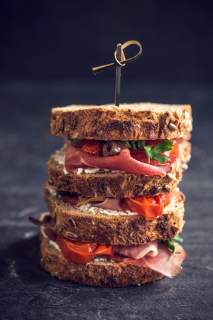 Served big toast sandwich stuffed with cream cheese,prosciutto and grilled tomatoesの写真素材