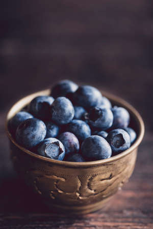Group of blueberries in the old metal cup on wooden background,selective focus の写真素材