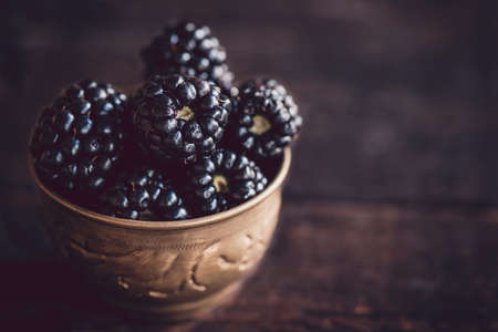 Group of blackberries in the old metal cup on wooden background,selective focus の写真素材