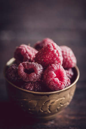 Group of rasberries in the old metal cup on wooden background,selective focus の写真素材