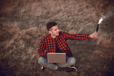 Happy man with the torch and laptop compiuter outdoorの写真素材