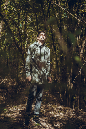 Hipster deep in the woods looking on lightの写真素材