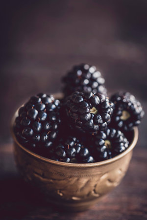 Group of blackberries in the old metal cup on wooden background,selective focusの写真素材