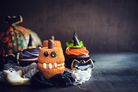 Funny and scary Halloween cup cakes on wooden background with blank spaceの写真素材