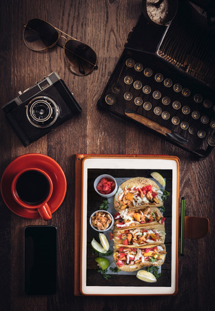 Food blog concept with tortilla sandwiches on tablet pc on wooden deskの写真素材